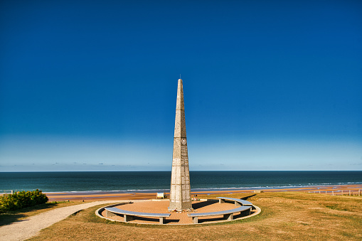 Omaha Beach, Colleville-sur-Mer, France, September 01, 2019:  Looking at the 1st US Infantry Division Memorial at Omaha Beach, Colleville-sur-Mer, Calvados, Normandy, France. The obelisk stands in the middle of the area of Wiederstandsnest (WN62). WN62 was one of the strongest defending positions in that area. The WN62-area is dotted with casemates, tobruks, trenches and other defense objects.