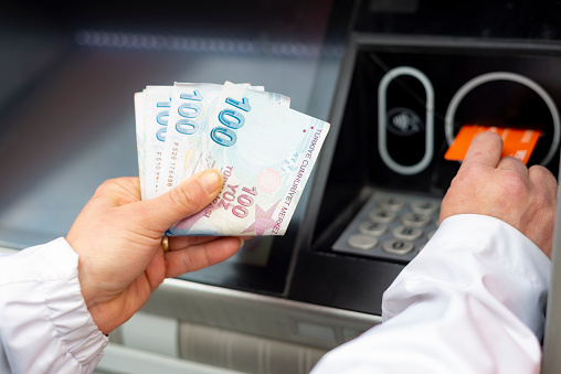 Woman deposits money in ATM with Turkish currency.