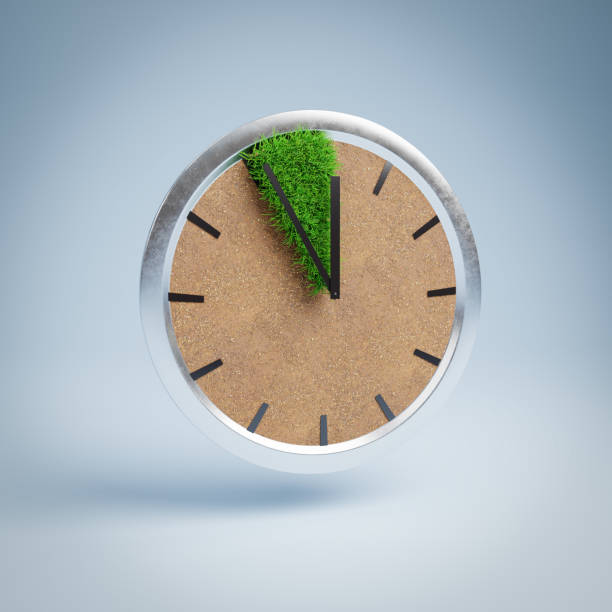 Time is running out for acting against the climate crisis. It is 5 minutes to twelve. Concept shot showing a clock with arid soil and a small patch of grass land in the remaining time frame. stock photo