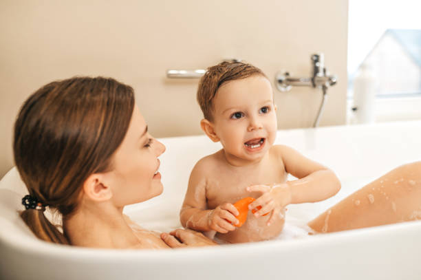 istock Young female parent taking a bath with her baby boy 1389142492
