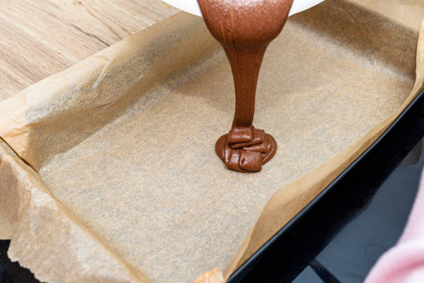 istock Pouring a liquid thick mass of cocoa dough onto a baking sheet lined with baking paper. 1389146150