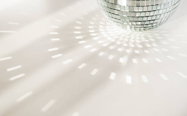 Disco ball on a white background with shadows and casts rays of bright light. Glare and light reflection Disco ball on a white background with shadows and casts rays of bright light. Glare and light reflection effect. Copy space. glitter ball stock pictures, royalty-free photos & images
