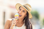 Beautiful happy woman licks ice cream during a hot summer day.