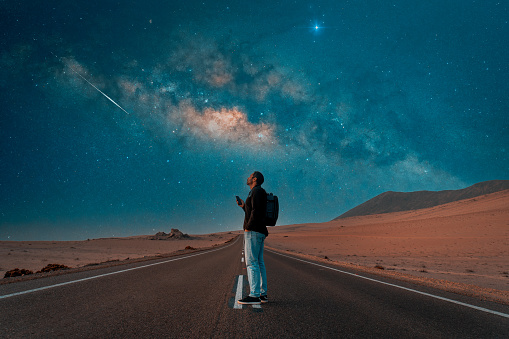 person standing on the road under milky way at night