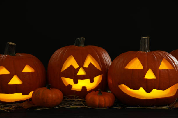 istock Glowing jack o'lanterns on table in darkness. Halloween decor 1389149635