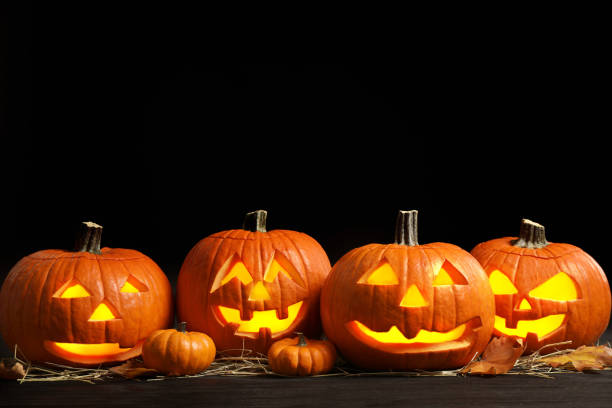istock Pumpkin jack o'lanterns on table in darkness, space for text. Halloween decor 1389149787