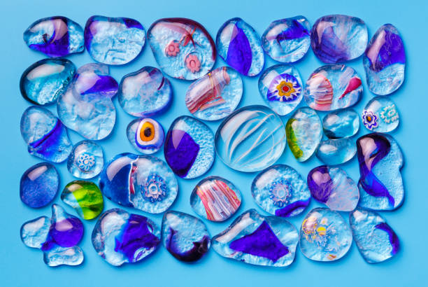 coleção de contas de vidro coloridas de diferentes tamanhos e formas. veneziano colorido, murano de vidro, millefiori. em um fundo azul - overhand - fotografias e filmes do acervo
