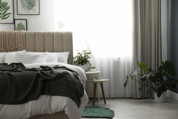 istock Comfortable bed with warm knitted plaid in stylish room interior 1389149884