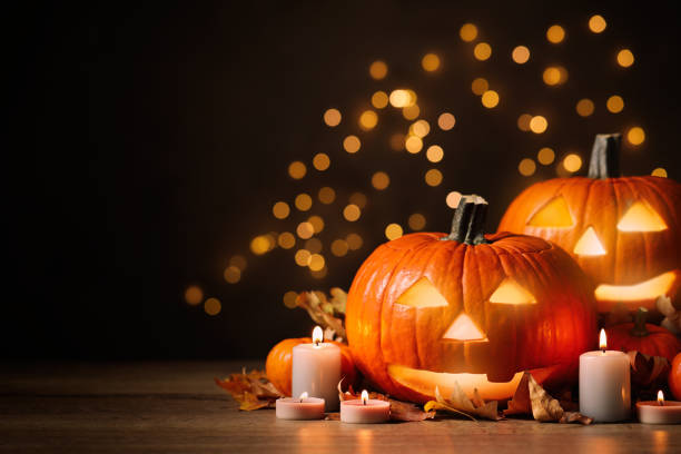 istock Pumpkin jack o'lanterns, autumn leaves and candles on table against blurred background, space for text. Halloween decor 1389149936