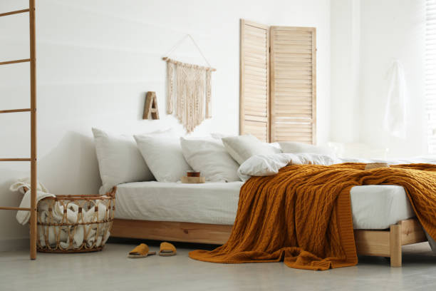 istock Comfortable bed with warm knitted plaid in stylish room interior 1389150165