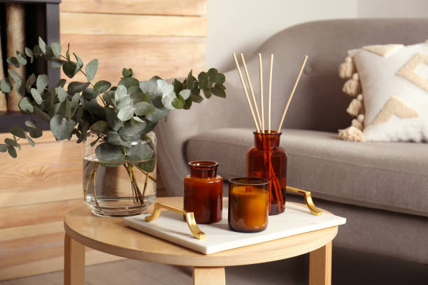 eucalyptus branches, aromatic reed air freshener and candles on wooden table in living room. interior element - aromatic oil burner imagens e fotografias de stock