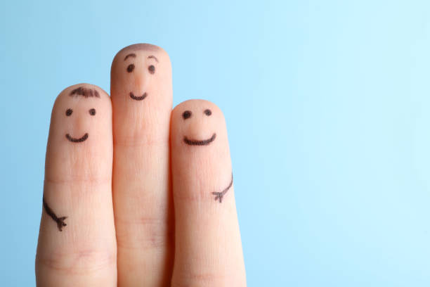 istock Three fingers with drawings of happy faces on light blue background, space for text 1389152765
