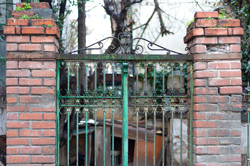 Iron security gates to a home. Rusty iron gate between old stonewall.