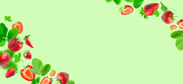 Ripe fresh flying red strawberry, green leaves isolated on green background. Strawberry pattern Summer delicious sweet berry organic fruit food diet vitamins creative layout. Whole and halved berries