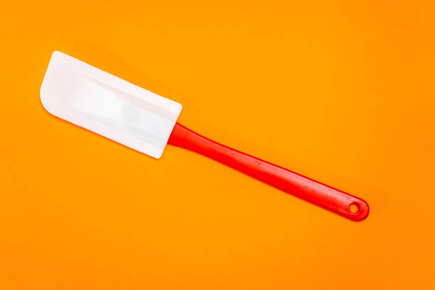istock Red and white kitchen spatula made of silicone and plastic insulated on a orange surface 1389157090