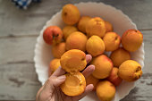 Female hands cutting fresh sweet peaches to make peach jam.