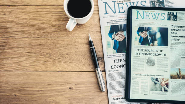 Newspaper and digital tablet on wooden table stock photo