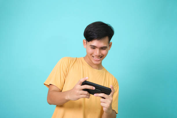 Young man using mobile phone playing online game stock photo