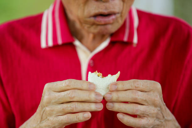 An Asian senior man is eating the bread