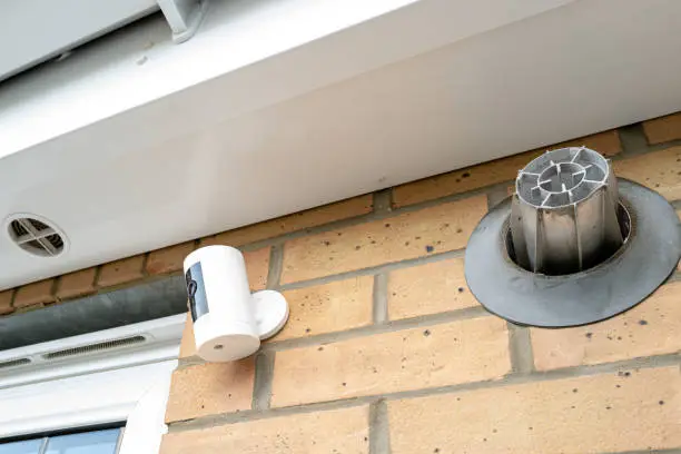 Newly installed, battery-powered wireless Internet-of-Things security camera installed near a ground floor kitchen window, under the eaves.