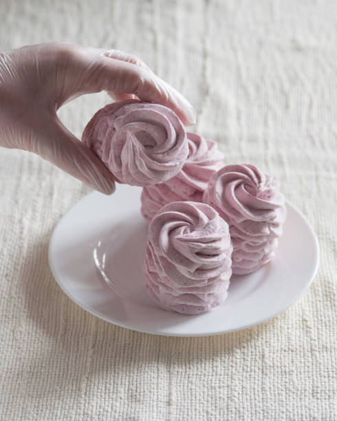 istock A woman's gloved hand takes marshmallow from a white plate, lihgt background, selective focus 1389162700