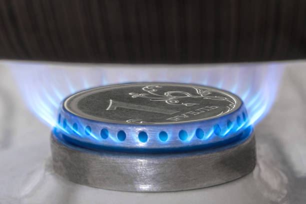 gasbrenner und rubelmünze, russisches geld auf dem gasherd zu hause. blaue propangasflamme und rubelwährung. konzept der russischen und europäischen wirtschaft, erdgaskosten, inflation, sanktionen und zahlung. - flame gas natural gas blue stock-fotos und bilder