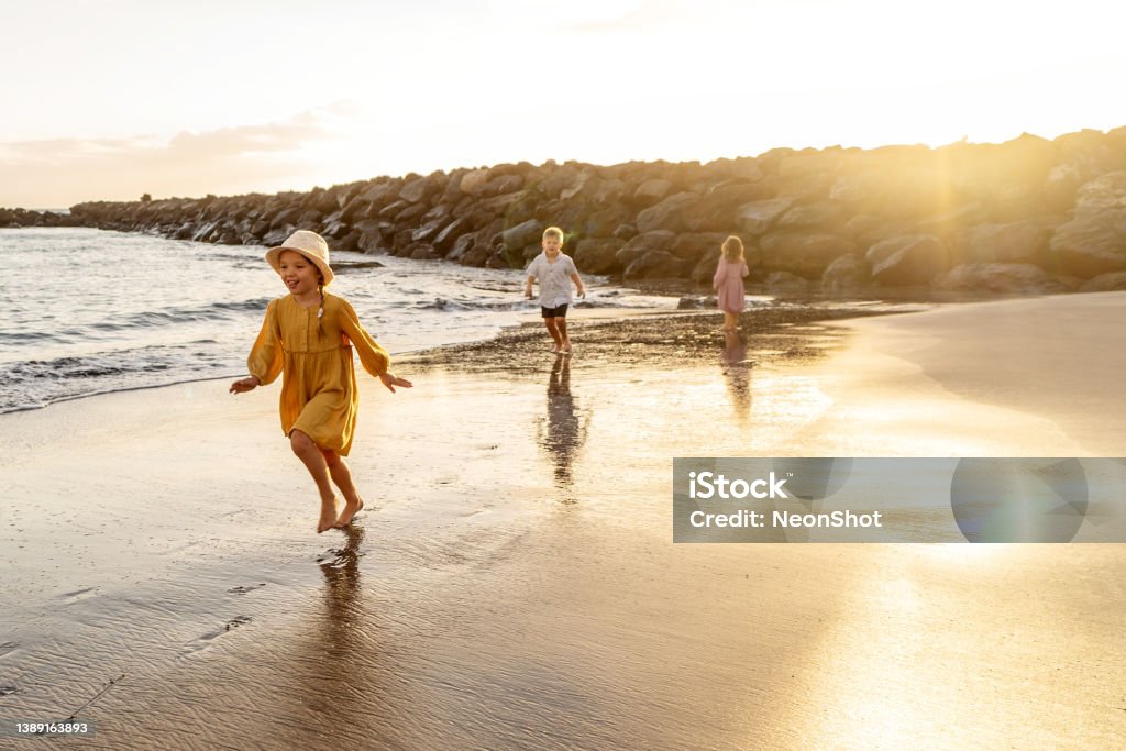 Kids playing on the beach. Family summer vacation vibes. Kids playing on the beach. Little boy and girls running at sea shore at sunset. Family summer vacation vibes. A lot of copy space. Tenerife Stock Photo