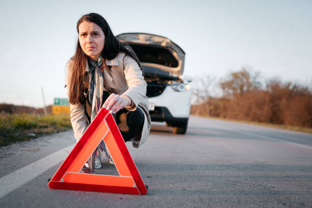 istock Woman setting up a warning triangle after her car broke down 1389166234