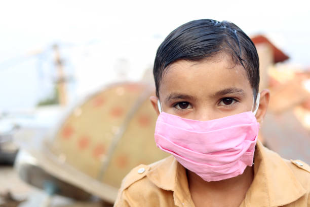 Poor elementary age child wearing face mask during pandemic portrait close up at home.
