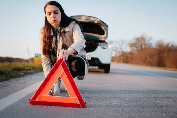 istock Woman setting up a warning triangle after her car broke down 1389166341