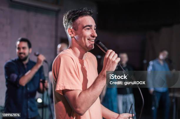 Smiling And Witty Stand Up Actor Comedian On Stage Talking And Singing Stock Photo - Download Image Now
