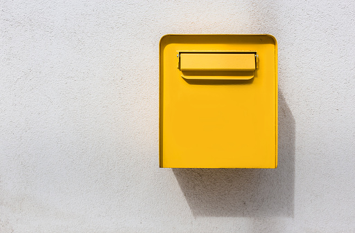 Yellow mailbox on white wall. Retro style