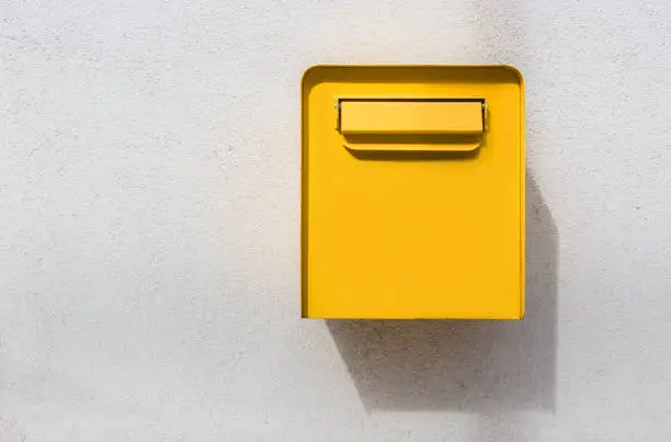 Yellow mailbox on white wall. Retro style