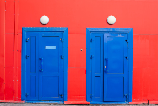 a blue doors on a red wall with a lamp
