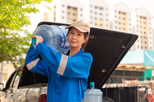 Portrait of an Asian female courier making a bottled water delivery to resident home and office.