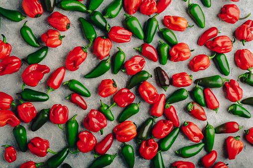 Colorful Hot Jalapeno and Habanero Peppers on Concrete Countertop. View from Above