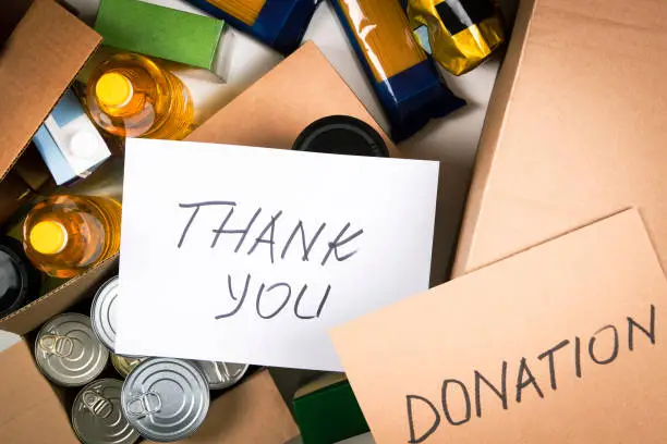 Photo of Food donations boxes with grocery products and cards with inscription Donation and Thank you. Cardboard boxes with oil, canned food, cereals, pasta, water. Top view