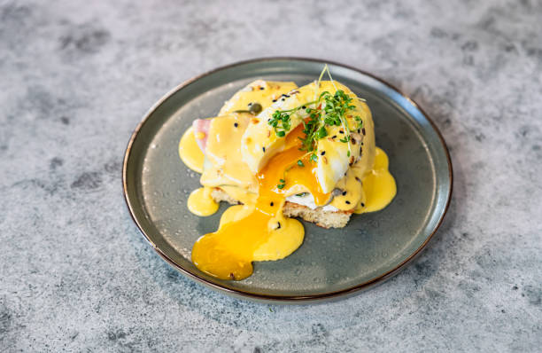 istock Crispy toast with ham, poached egg, mashed avocado and hollandaise sauce decorated with microgreen 1389177430