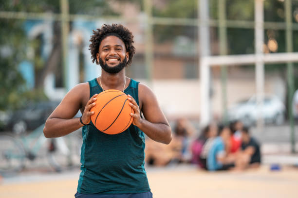 смеющийся человек держит баскетбольный мяч - basketball young men sport 20s стоковые фото и изображения