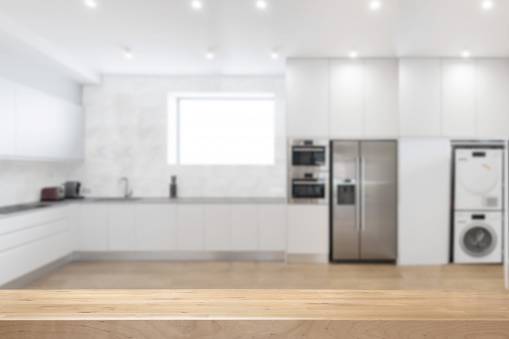 White kitchen interior background with appliances and selective focus on wooden surface