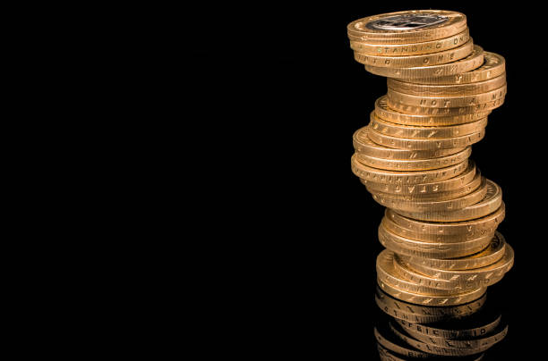 стопка золотых монет великобритании на черном фоне - one pound coin british currency coin paper currency стоковые фото и изображения