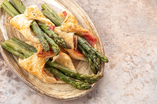 Baked green asparagus with bacon ham and cheese in puff pastry