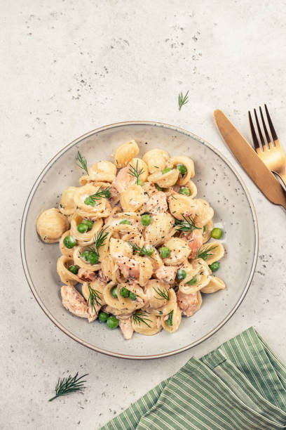 orecchiette pasta mit geräuchertem lachs, grünen erbsen und cremiger sauce - orecchiette stock-fotos und bilder
