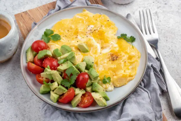 Scrambled eggs omelet with cherry tomatoes and avocado