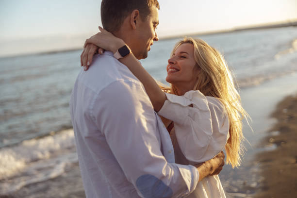 istock Portrait of happy couple hugging while standing on beach 1389187559