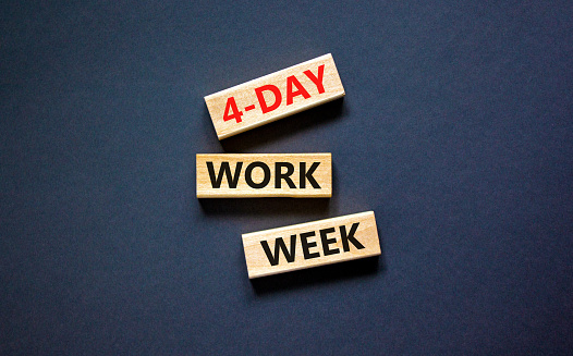4-day work week symbol. Concept words 4-day work week on wooden blocks on beautiful black table black background. Copy space. Business and 4-day work week and short workweek concept.
