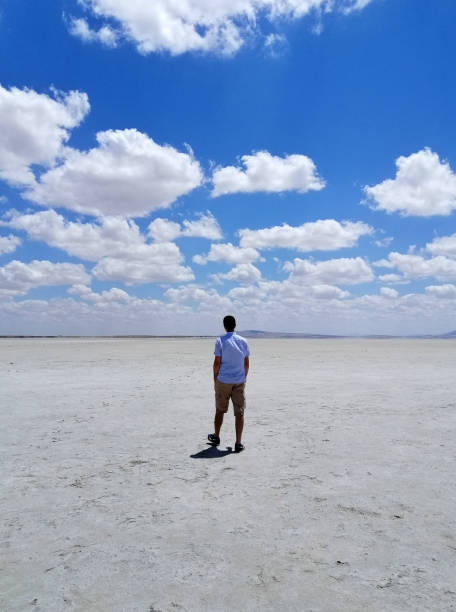 Seyfe Lake dry lakebed Kırşehir, Turkey - July 11, 2021: Young man walking on Seyfe Lake which is a shallow, 15 km² tectonic lake located 35 kilometers east of Kırşehir. It is seen that Lake Seyfe, whose water decreases in summer, swells in winter due to heavy rainfall and turns into a swamp around it. Around 25 bird species also visit the "Bird Paradise", where 50 different bird species incubate and 182 bird species shelter during migration. lakebed stock pictures, royalty-free photos & images