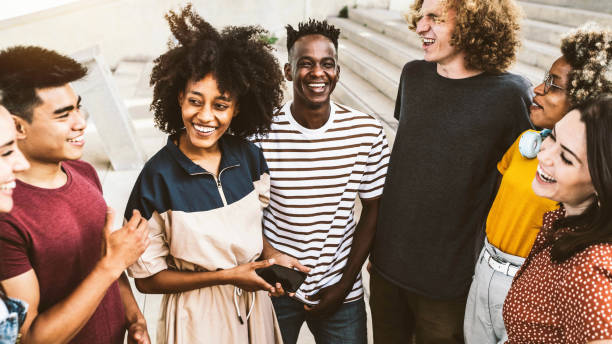 migliori amici multirazziali che si divertono a ridere ad alta voce all'aperto - gruppo di giovani che si godono la giornata estiva - adolescenti che scherzano insieme nel campus universitario - concetto di amicizia - teenager city life laughing group of people foto e immagini stock