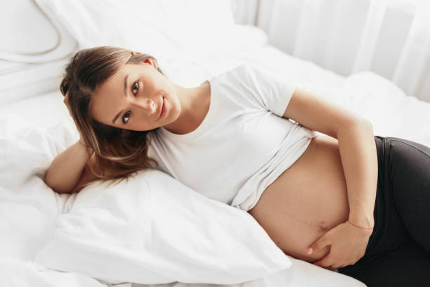 istock Happy pregnant woman lying on bed 1389206454