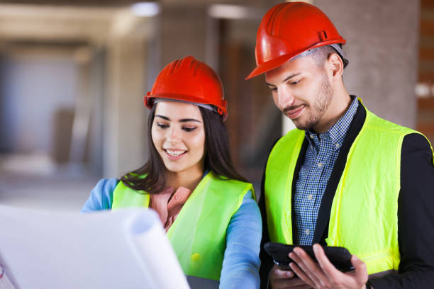 istock construction site engineers with blueprints and tablet wearing hard hats 1389209265